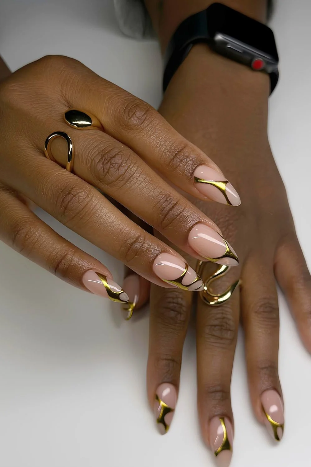 Neutral almond nails with gold chrome swirls