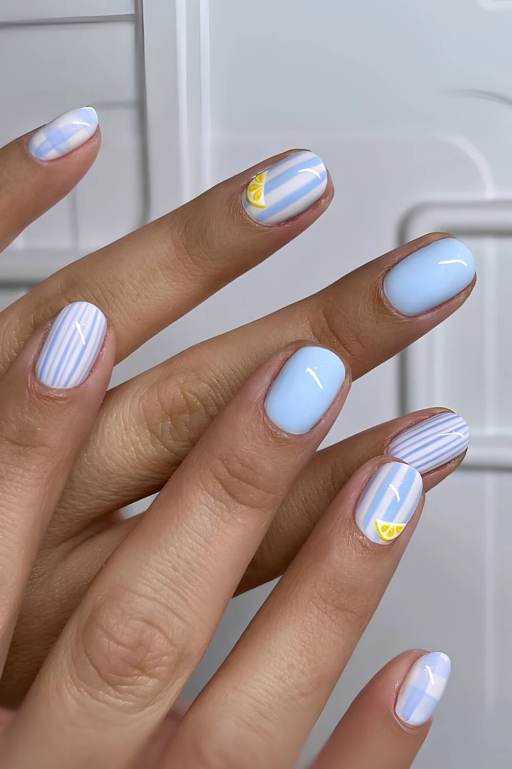 Light blue nails with stripes, gingham and lemon slice accents