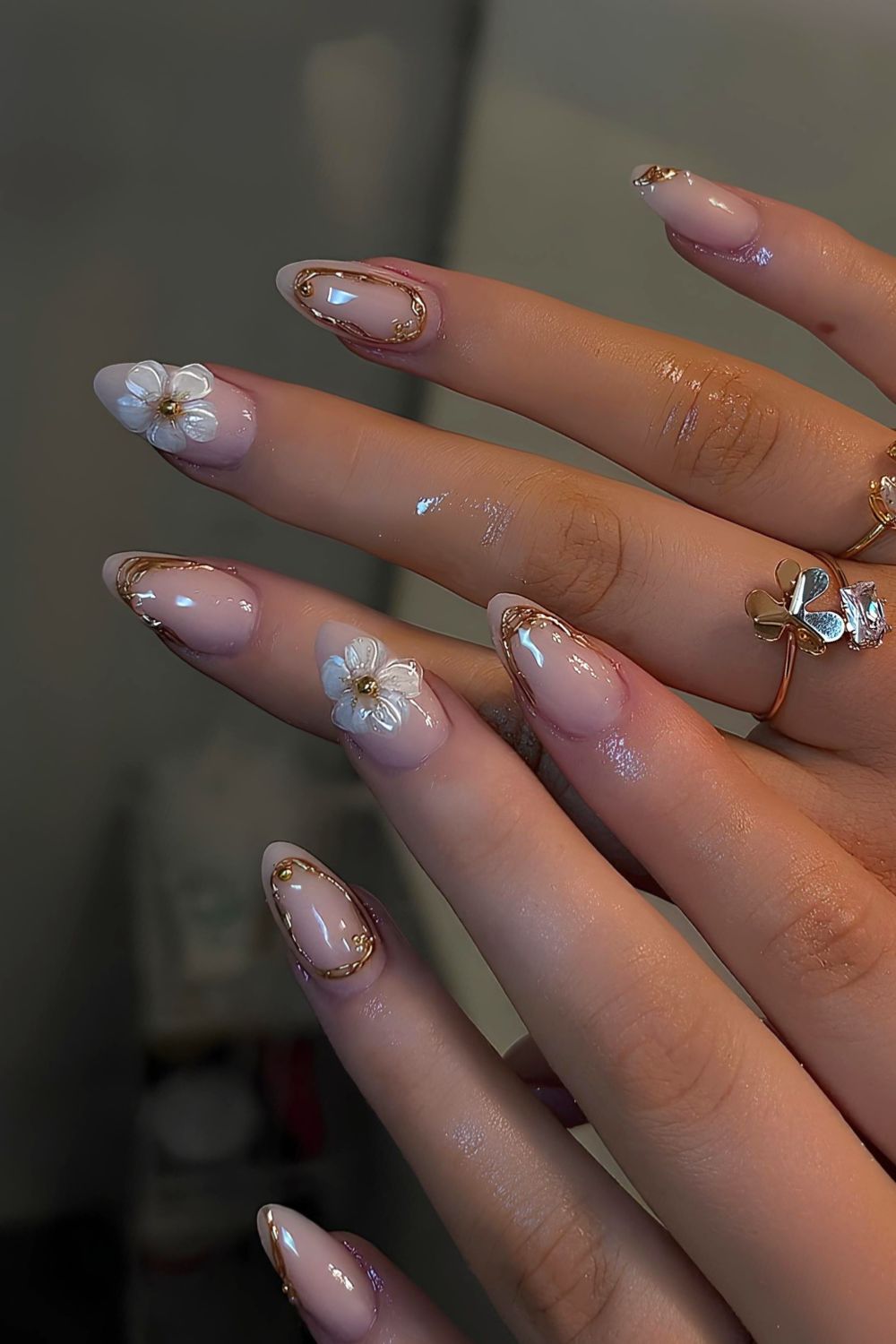 Neutral glossy nails with chrome accents and sculpted white florals