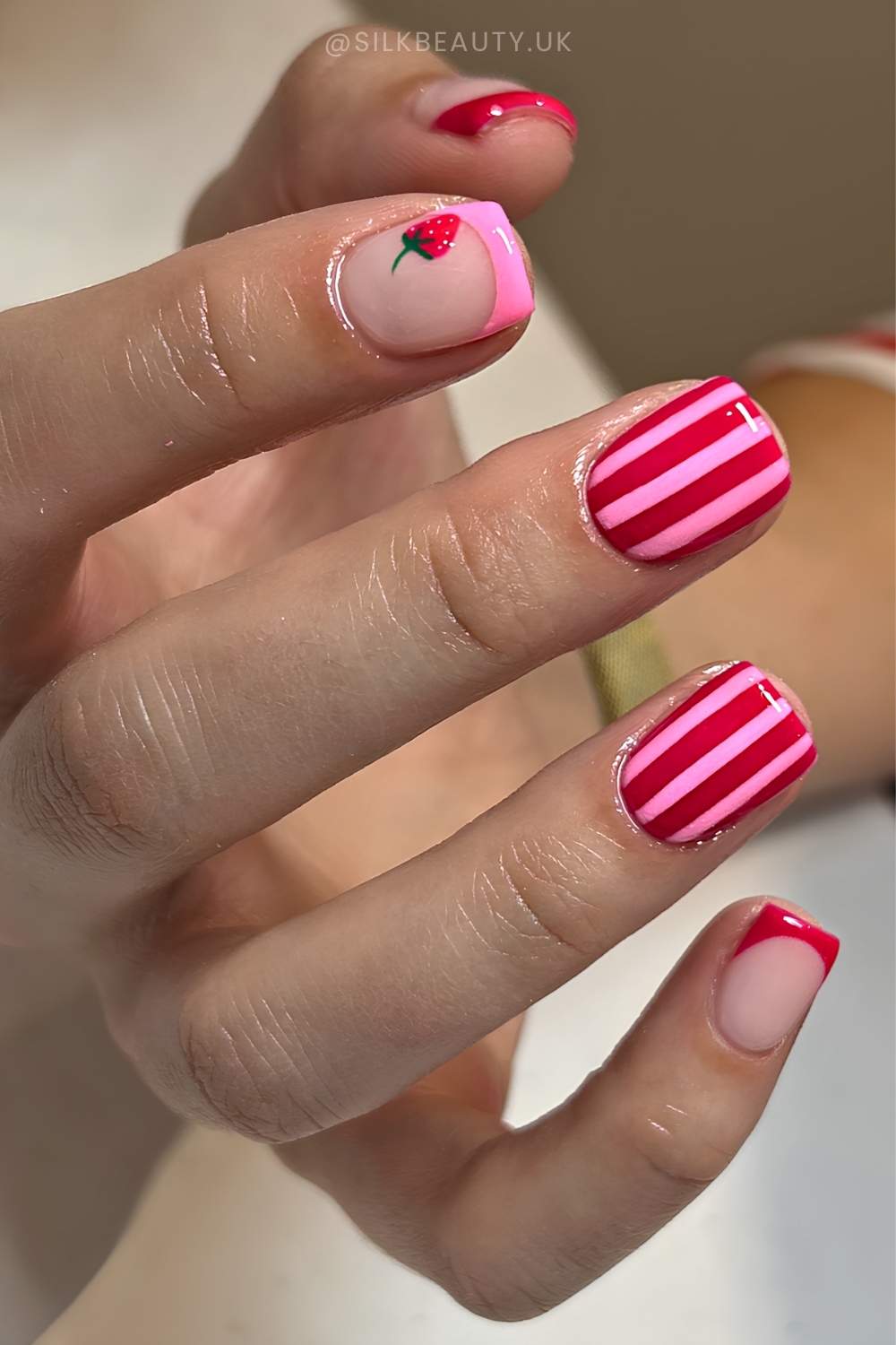 Pink and red nails with strawberries and stripes
