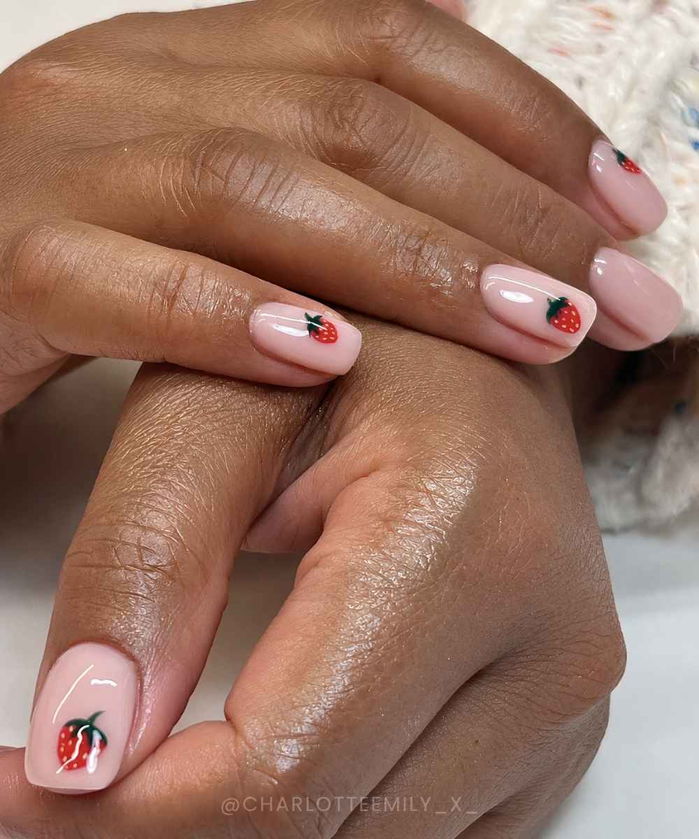 Short milky pink nails with strawberry art