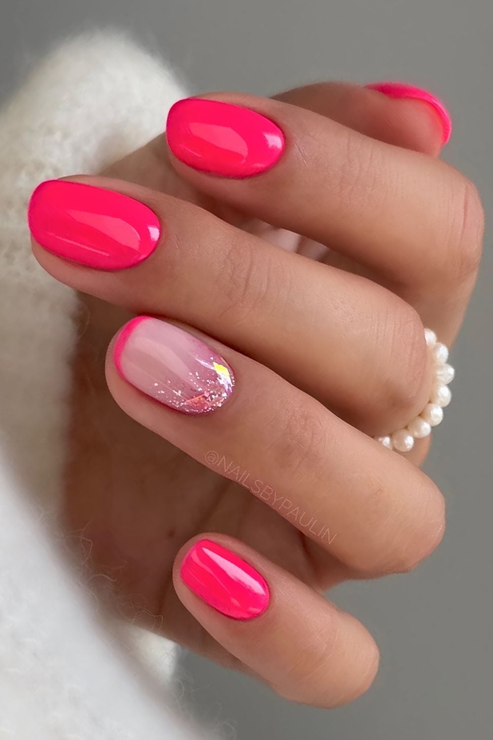 Short neon pink nails with glitter accent