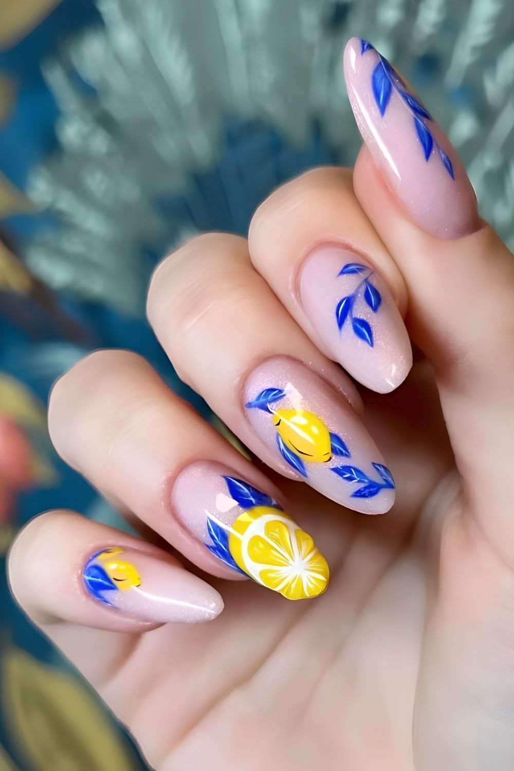 Soft pink glittery base with blue leafs and lemon nail art