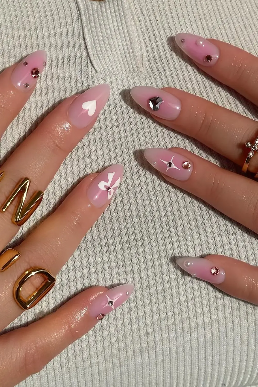 Blush pink nails stacked with white hearts, nows and rhinestones