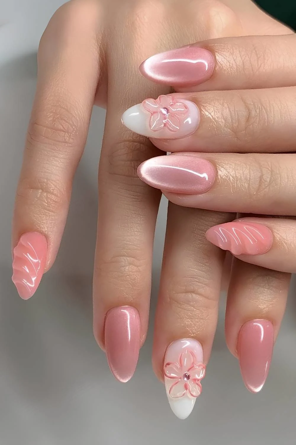 Bright pink cat eye nails with floral accents