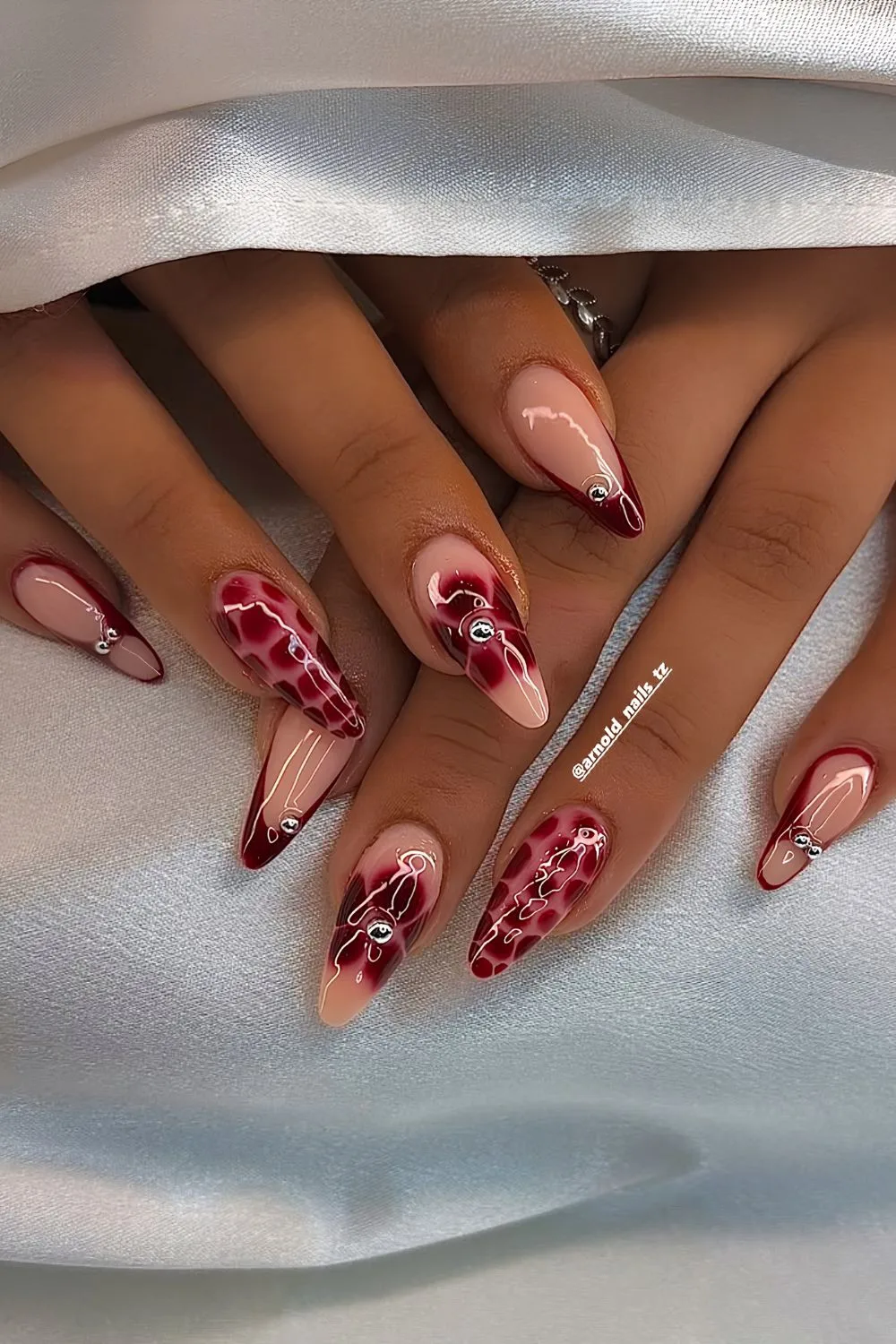 Cherry red mani with blooming floral accents and studs