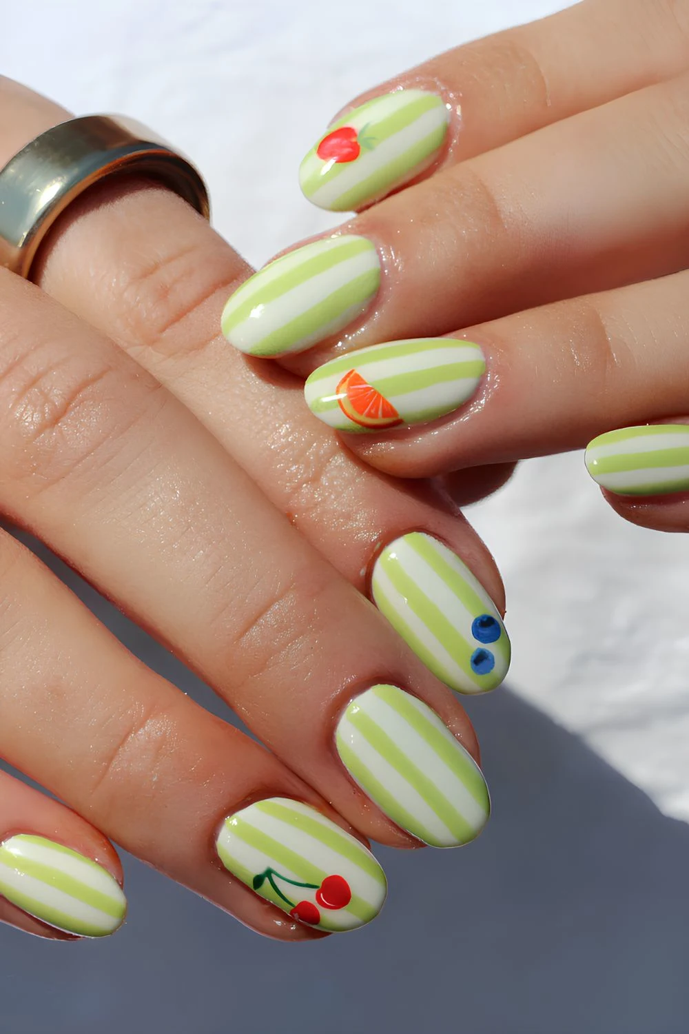Lime green and white stripe nails with fruit decals