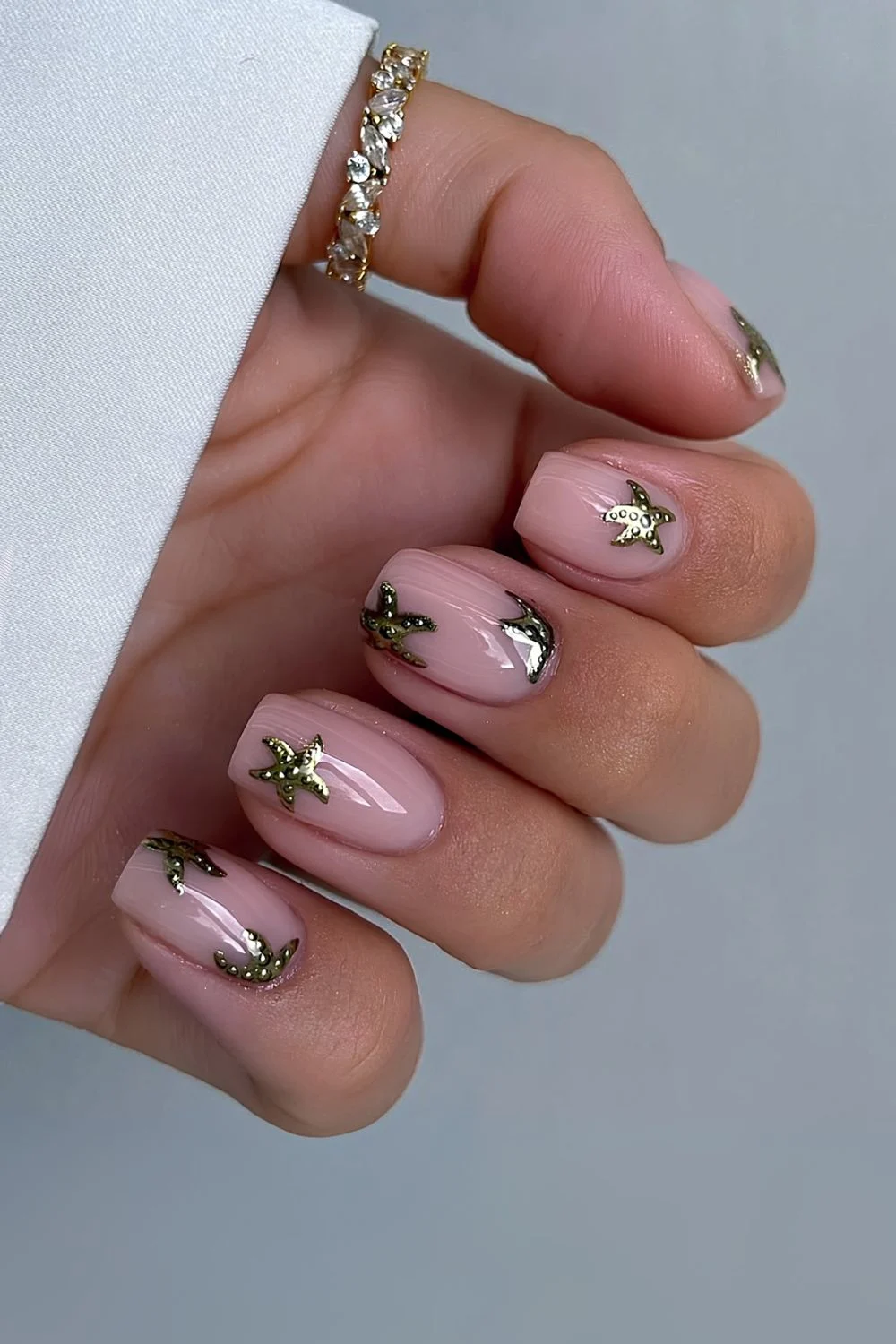 Milky pink nails and gold chrome starfish design