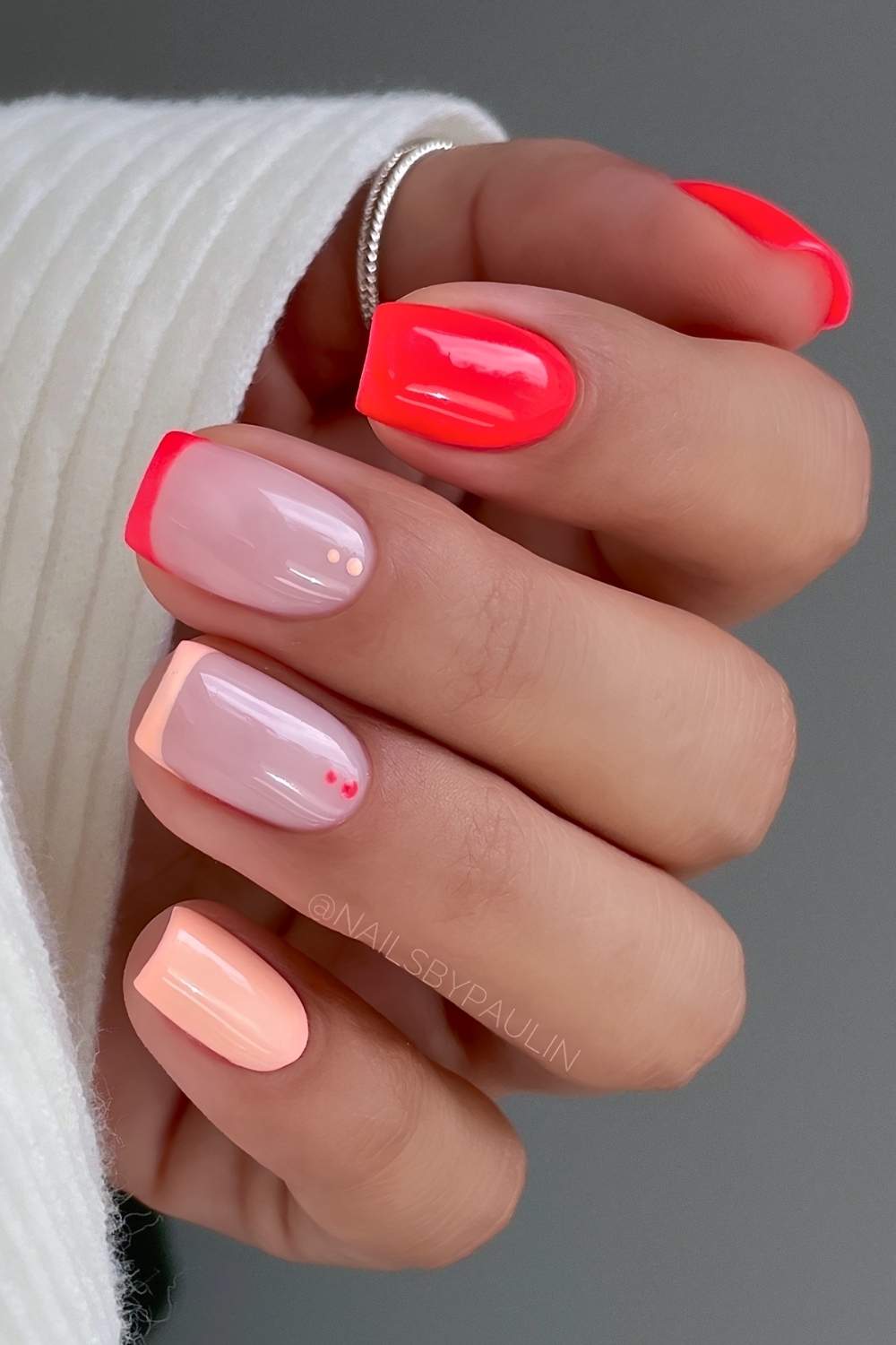 Neon red and pastel orange nails with dot accents