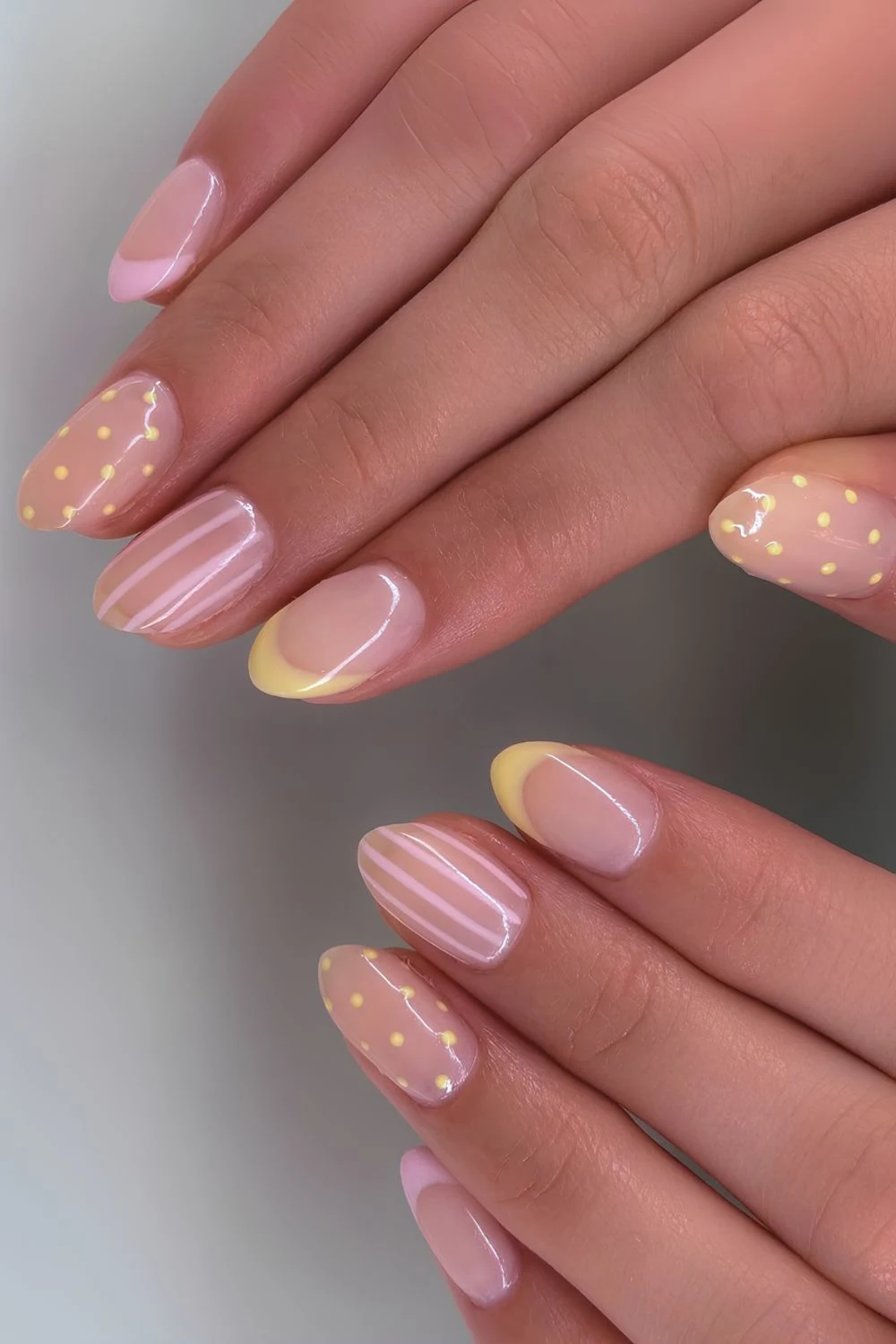 Pink and yellow nails with stripes and polka dots