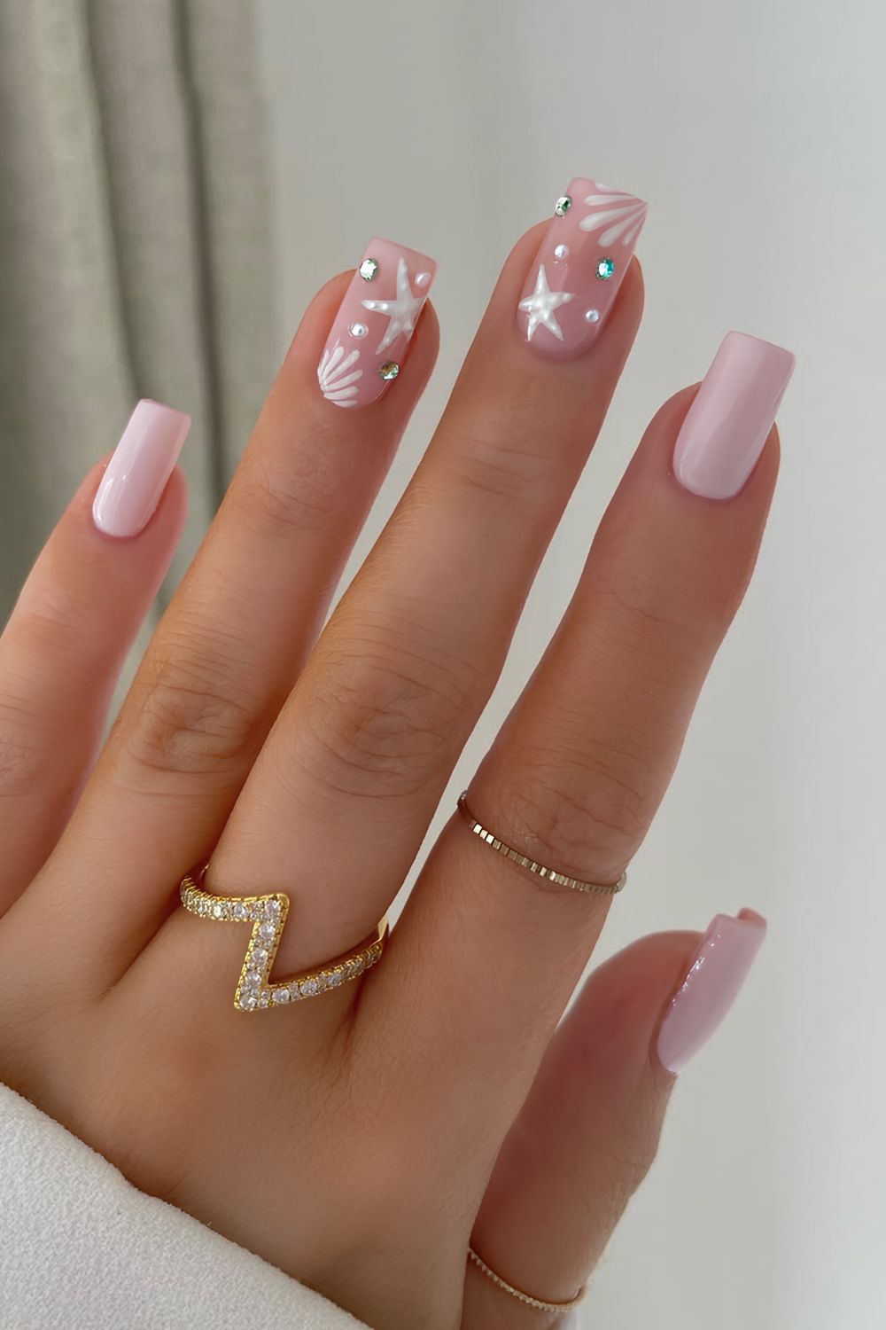 Soft pink nails with white starfish and gem accents