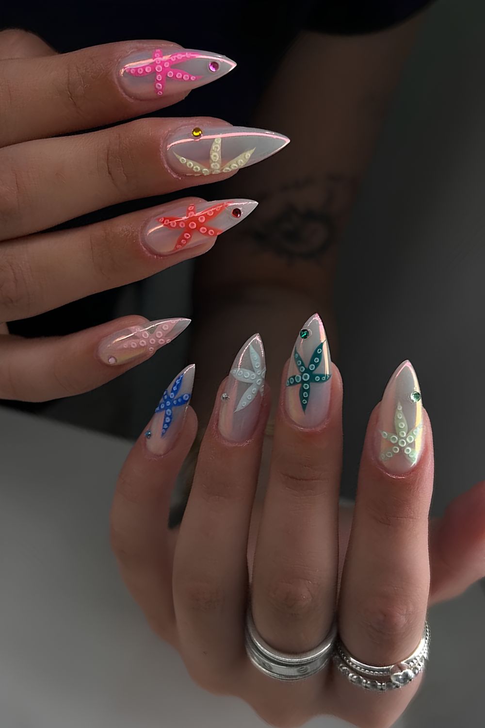 White iridescent chrome nails with large colorful starish design on each nail
