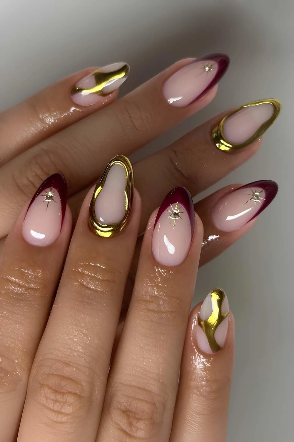 Maroon nails with gold chrome accents