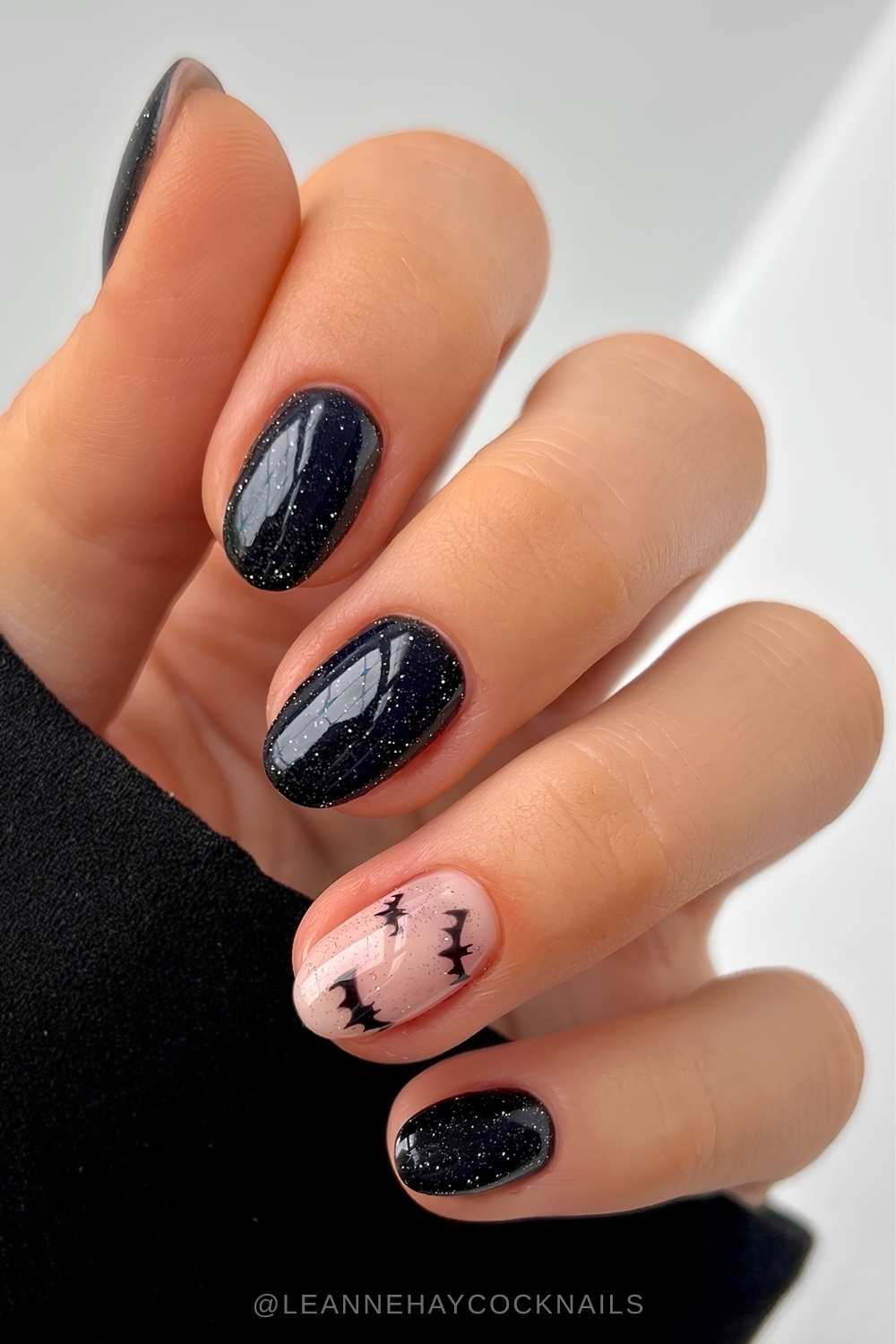 Shimmery black nails with bat wing art