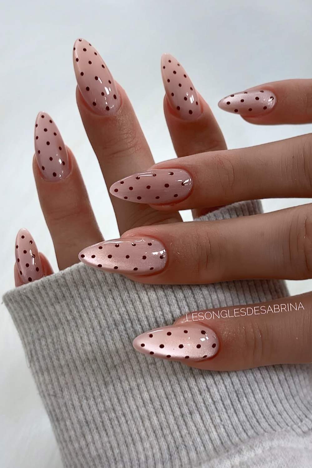 Pale pink cat eye nails with brown polka dots
