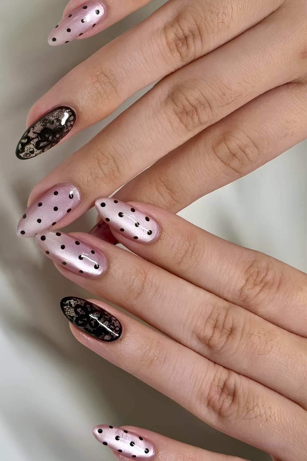 Pink cat eye nails with black dots and lace art