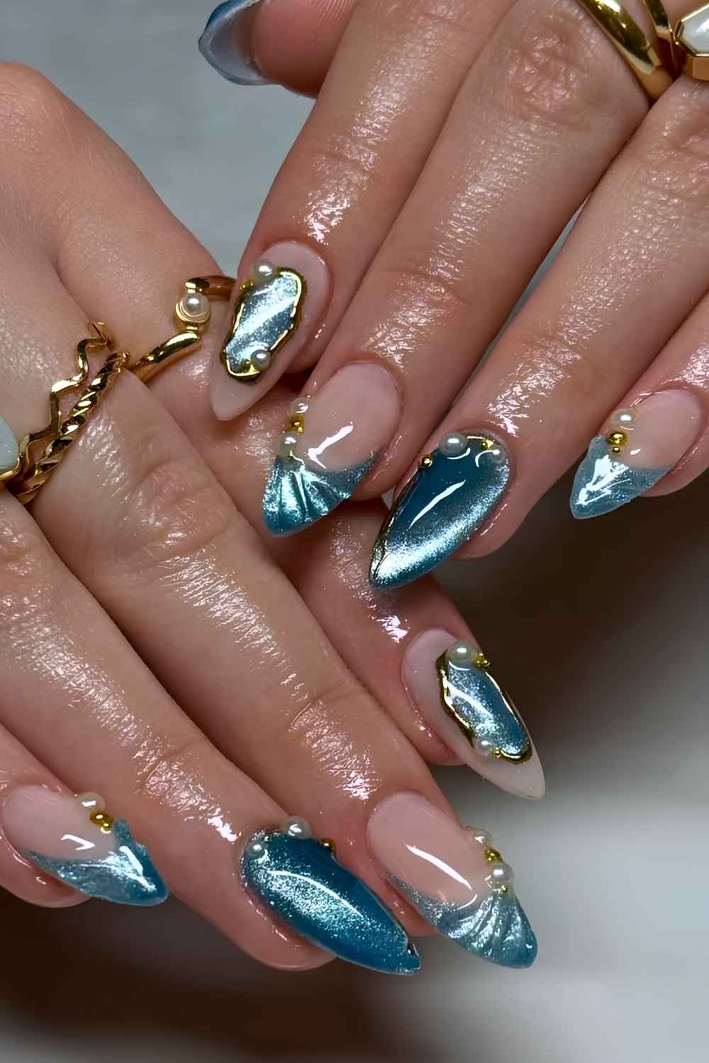 Blue cat eye nails with gold and pearl accents