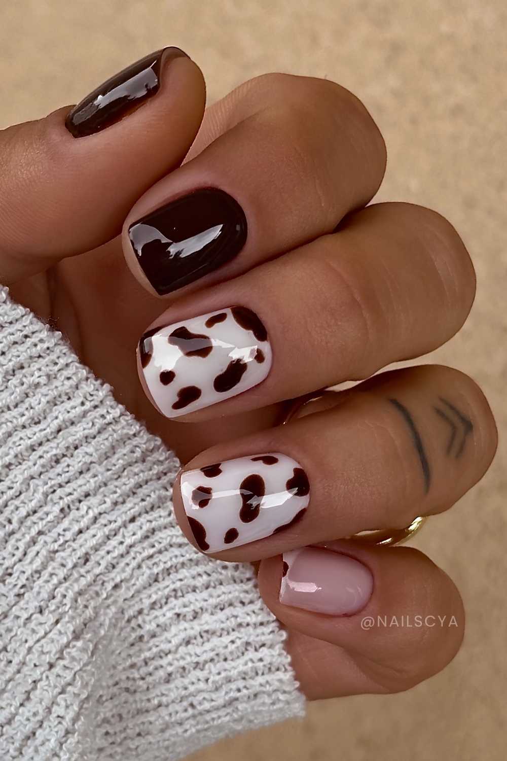 Dark brown and white nails with cow print
